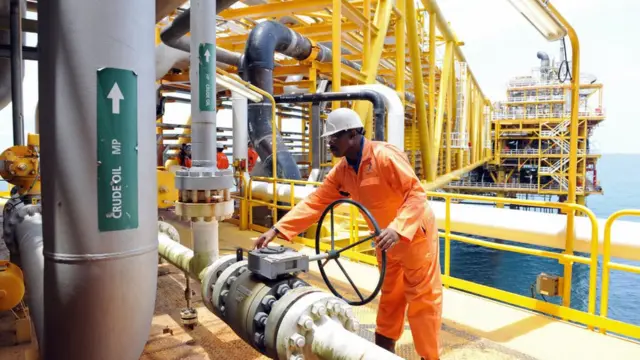 Oil worker wey dey inspect drilling facility