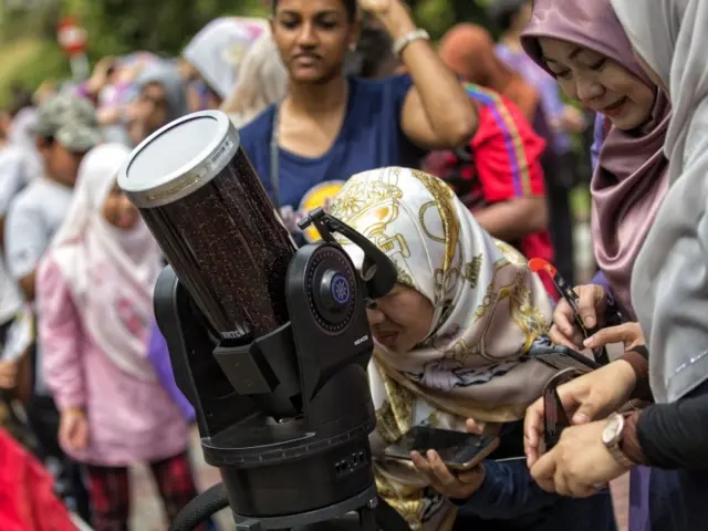ผู้หญิงคนหนึ่งชมปรากฏการณ์สุริยุปราคาผ่านกล้องโทรทรรศน์ที่ด้านนอกหอดูดาวในกรุงกัวลาลัมเปอร์ของมาเลเซีย 26 ธ.ค. 2019