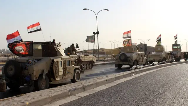 A convoy of Iraqi military trucks flying religious Shiite flags and Iraqi national flag as they advance into the central of Kirkuk city, northern Iraq