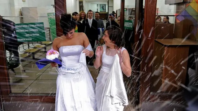Dos mujeres vestidas de novia saliendo del Registro Civil de Uruguay tras casarse.