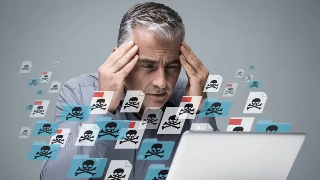 Hombre frente a pantalla de computadora que pareciera infectada de virus.