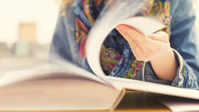 Mujer pasa hojas de un libro.