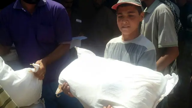 Niño refugiado con un saco de alimentos