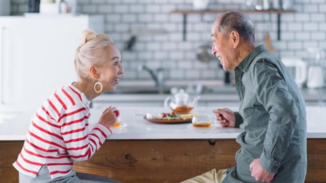A woman and a man sit and speak face to face at a breakfast bar