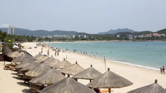 People sit under umbrellas on the beach in the Dadonghai district of Sanya, Hainan Province, China, on Monday, April 7, 2014