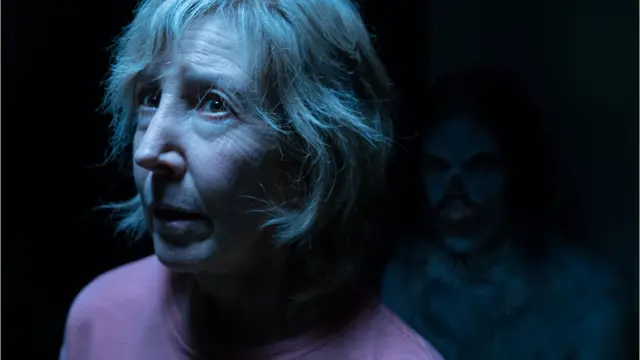 A monster character lurks in the background of a shot