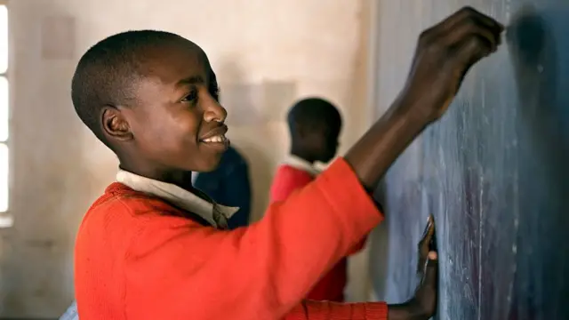 Nwata akwụkwọ na-ede ihe na bọd