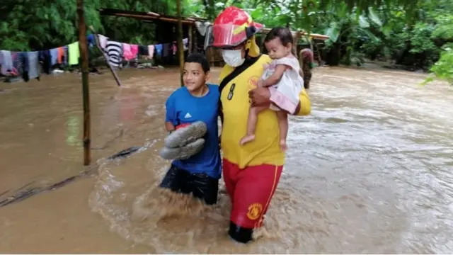 Bomberos rescatan unos niños en Honduras por la crecida del río.