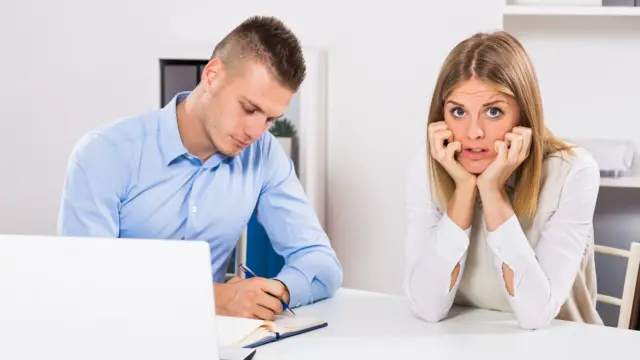 Una joven con cara de terror, junto a otro joven con una laptop