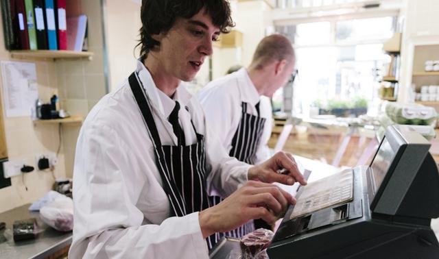 A butcher uses the till at a traditional butcher's shop in Dorset