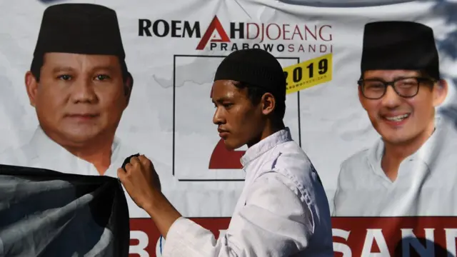 Seorang partisipan membentangkan baliho pasangan calon Presiden dan Wakil Presiden nomor urut 02 Prabowo Subianto dan Sandiaga Uno saat peresmian rumah pemenangan di Surabaya, Jawa Timur, Senin (22/10/2018).