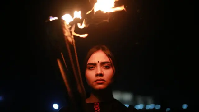 ঢাকায় মশাল হাতে একজন প্রতিবাদকারী, ১৪-১০-২০২০।