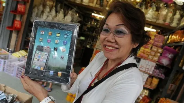 मृत व्यक्ति के लिए पेपर आईपेड और आईफोन लिए हुए चीनी महिला