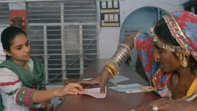 బ్యాంకు ఖాతా కోసం వేలిముద్ర వేస్తున్న ఓ మహిళ