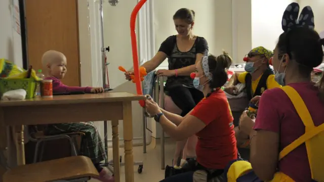 Клоуни дають повітряну кульку хворій дитині