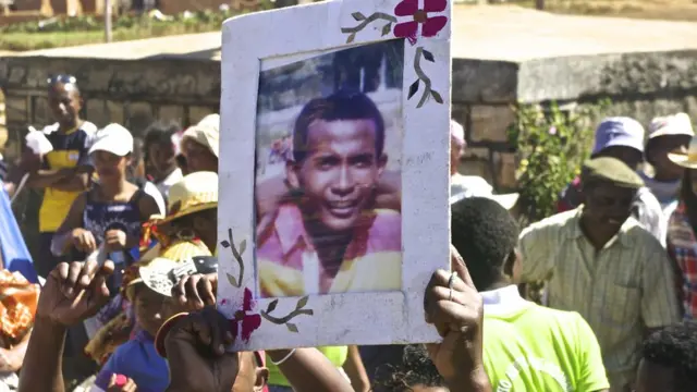 Les participants brandissent des photos des défunts pendant la cérémonie