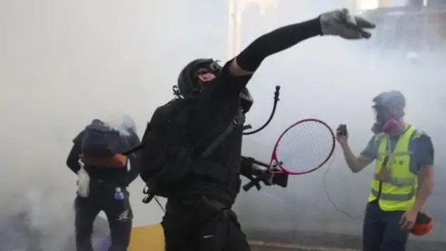 Demonstran melempar balik gas air mata ke arah petugas dalam protes di Hong Kong.