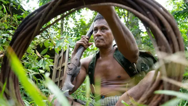 Mawi memegang senjata api dan sling baja yang digunakan untuk membunuh harimau.