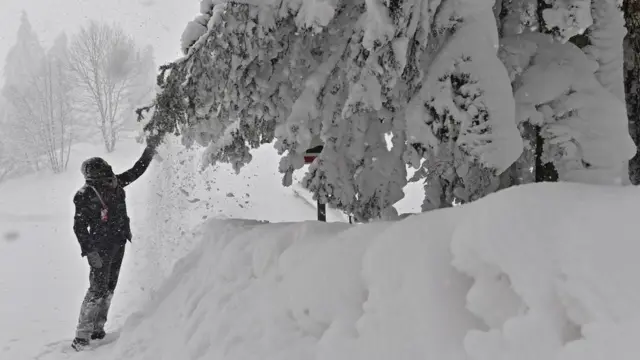 A person pulls at a snow covered branch after a heavy snowfall in Casaglia, Mugello, Florence's province, Italy, 27 February 2018.