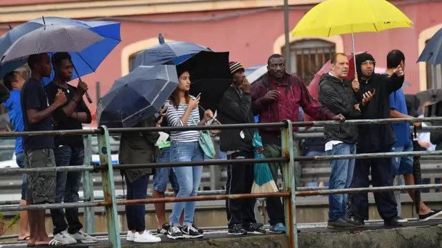прохожие в Генуе смотря на разрушенный мост