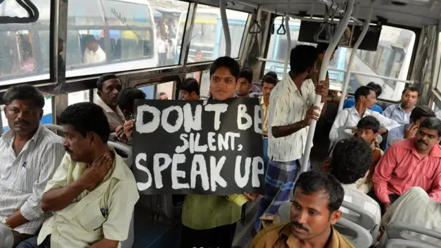 فتاة تحمل لافتة تطالب النساء بعدم السكوت عن التحرش