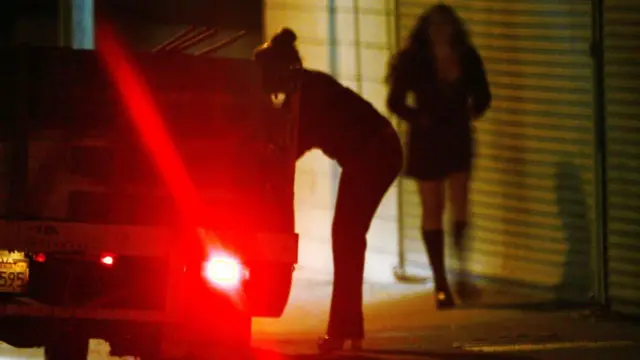 Mujeres en la calle junto a un carro.