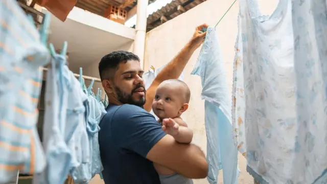 Pai lavando roupa e cuidandobebê