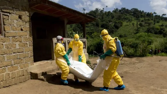 Des agents de la Croix-Rouge guinéenne portant des combinaisons de protection transportent le cadavre d'une victime d'Ebola à Macenta, le 21 novembre 2014