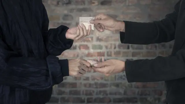 Personas intercambiando dinero por una bolsa con cocaína