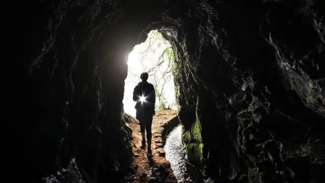 Una persona ante una cueva