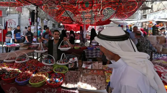 رجل يبيع الفاكهة والحلويات للاحتفال بالعيد في سوق شعبي في رفح، قطاع غزة.