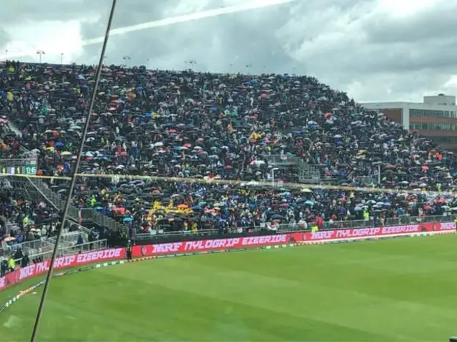 వర్షం కారణంగా గొడుగులు వేసుకున్న ప్రేక్షకులు