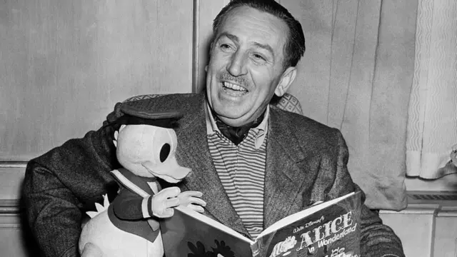 Retratoaplicativo betnacionalWalt Disney com boneco do Pato Donald e livroaplicativo betnacional'Alice no País das Maravilhas'