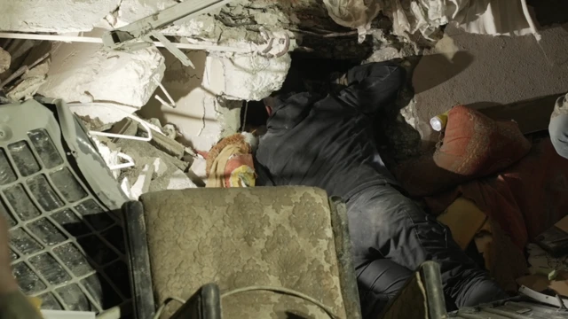 भग्नावशेषमा च्यापिएका दिदी बहिनीसँग कुरा गर्दै एक उद्धारकर्ता