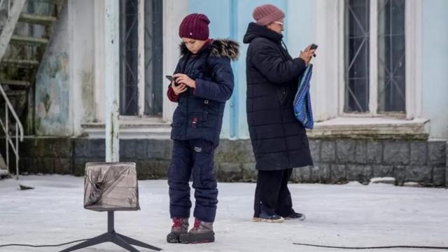 امرأة وطفل يستخدمان هاتفا خلويا