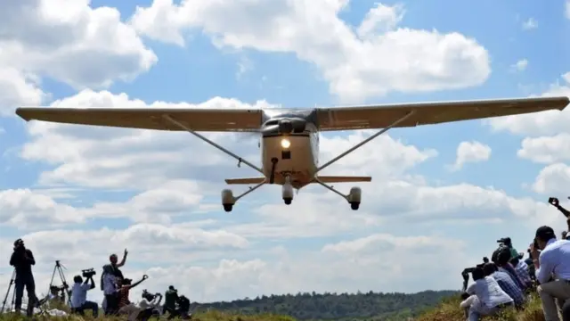 People take pictures and watch a vintage flying low over the Nairobi National Park, in Nairobi (27 November 2016)