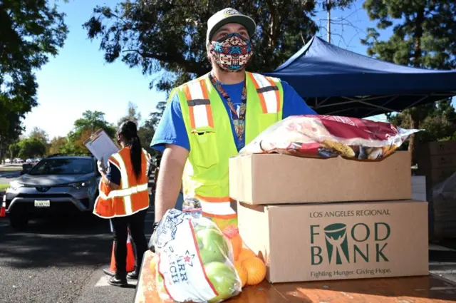 খাদ্য নিরাপত্তা অভাবে রয়েছে যেসব পরিবার তাদের জন্য সেচ্ছাসেবীরা খাবার দান করার জন্য গাড়িতে তুলছে ক্যালিঢোর্নিয়ার লস এঞ্জেলসে