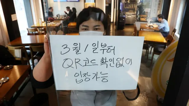 28일 서울의 한 식당 입구에 식당 관계자가 오는 3월 1일부터 시행되는 방역패스 적용 일시 중단 관련 안내문을 부착하고 있다