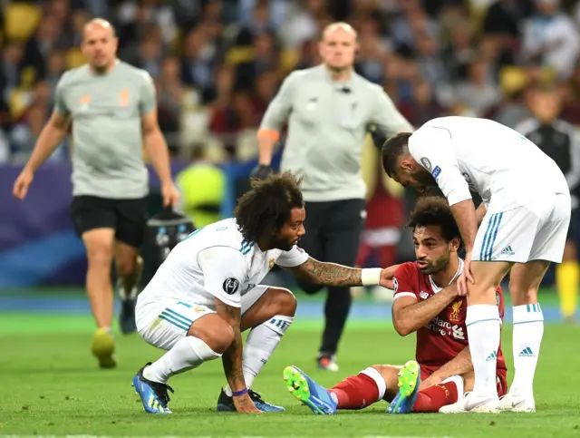 Игроки "Реала" Марсело и Даниель Карвахаль помогают нападающему "Ливерпуля" Мохаммеду Салаху, который упал, получив травму на поле