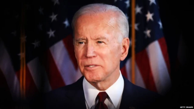 Joe Biden in front of US flags.