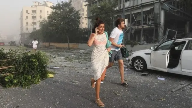 Abantu biruka bajya kwihisha nyuma y'iturika ku cyambu cya Beirut