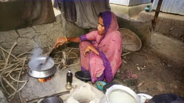 चूल्हे पर खाना बनाती एक महिला