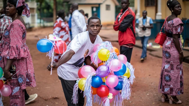 Wani mutum rike da tarin balan-balan da ake bai wa 'yan uwa da abokan arziki a kofar ofoshin magajin garin Bangui , a jamhuriar tsakiyar Afurka a ranar Lahadi 20 Maris 2021.