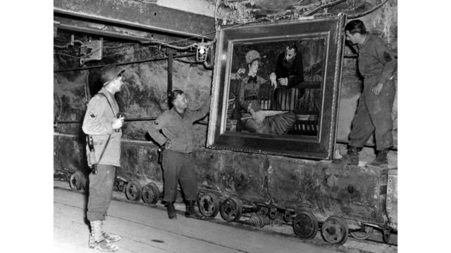 Нацисты прятали награбленное не только в Альтаусзее. Таких тайников у них было множество. На снимке: американские военные изучают полотно Эдуарда Мане "Зимний сад", обнаруженное в соляной шахте в немецком Меркерсе. 15 апреля 1945 г.
