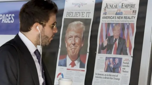 नतीजों के बाद ट्रंप के पोस्टर देखता एक अमरीकी