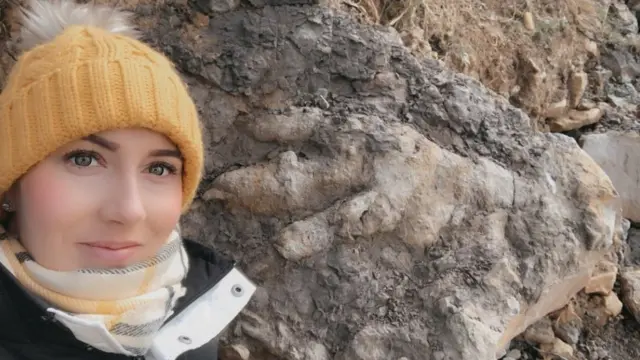 Photograph of Marie Woods next to footprint