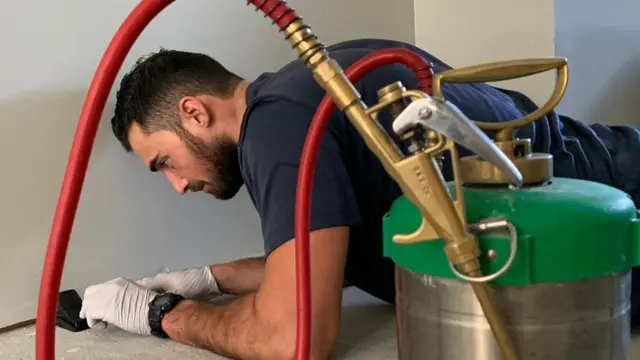 James Molluso lies on the floor to investigate a pest problem