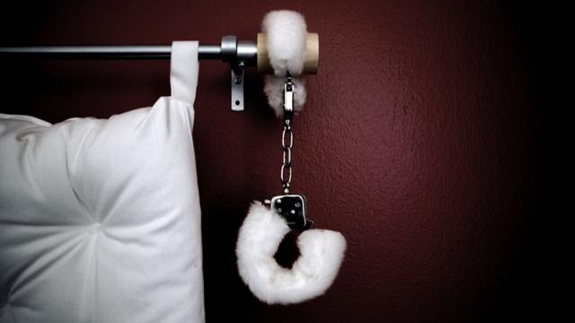 Handcuffs hang off the side of a bed