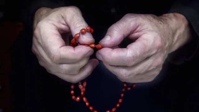 Mãos segurando um rosário