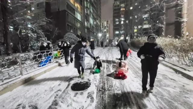 '아파트에서 눈썰매 타요'. 6일 밤 서울시내 한 아파트단지 내 눈 쌓인 도로에서 아이들이 눈썰매를 타고 있다